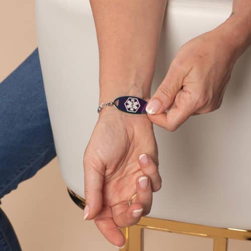 Model displaying the front of a Twilight medical ID bracelet featuring an iridescent alert tag with a bold medical symbol.