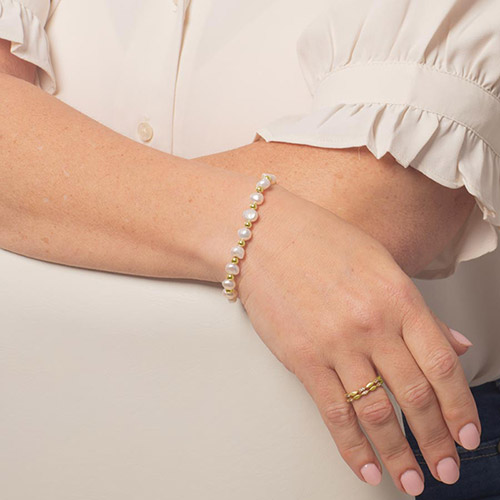 Freshwater pearl medical ID bracelet in gold styled on wrist for elegant everyday medical alert jewelry.