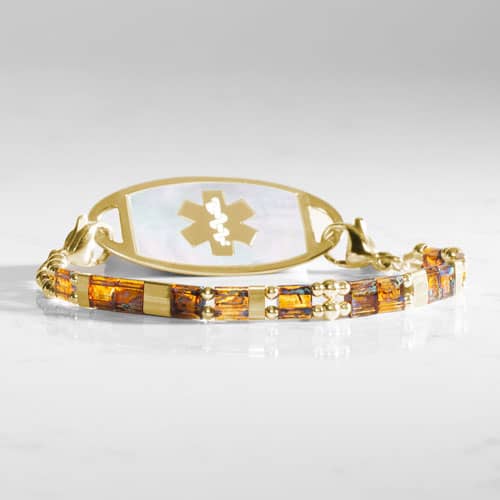 Gold-tone medical ID bracelet with amber-toned rectangular accents, decorative round beads, and a light inlay medical ID tag.