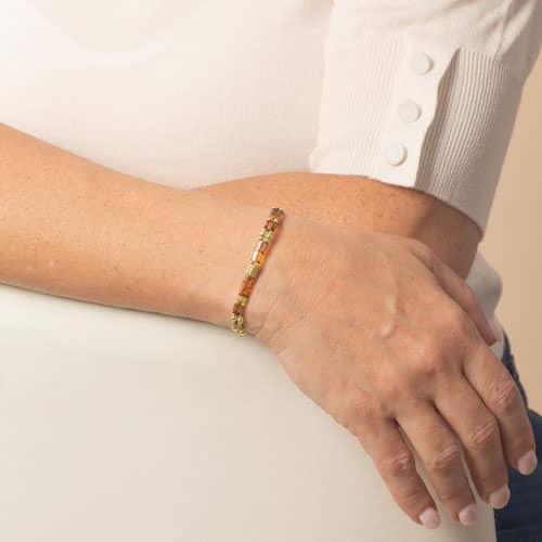 Model is wearing a slim bracelet with amber-toned rectangular accents and gold-tone details, showing its delicate profile on the wrist.