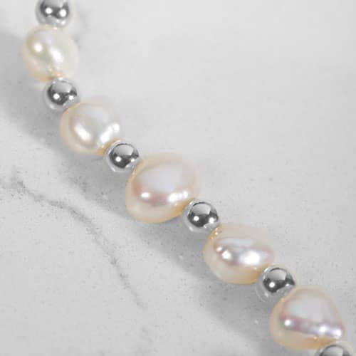 Close-up of freshwater pearl and Silver bead medical ID bracelet strand with luminous natural pearl detail.
