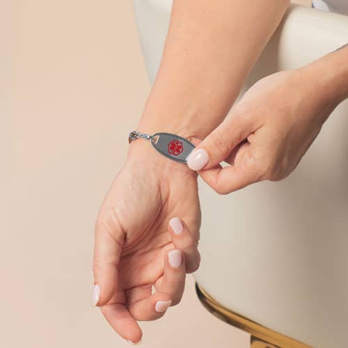 Person revealing the silver-tone medical ID tag with red Star of Life on the wrist.