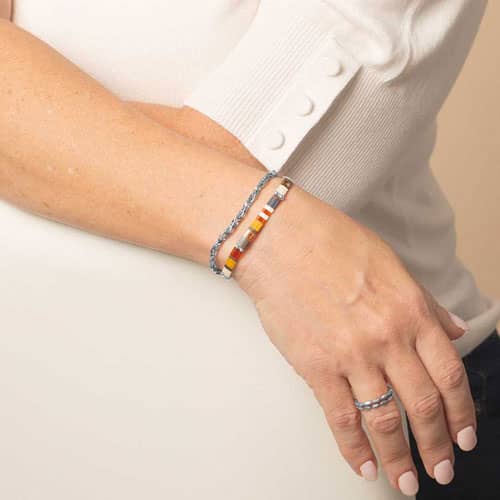 Model is wearing a two-strand silver-tone bracelet featuring colorful rectangular beads in orange, yellow, cream, brown, and blue.