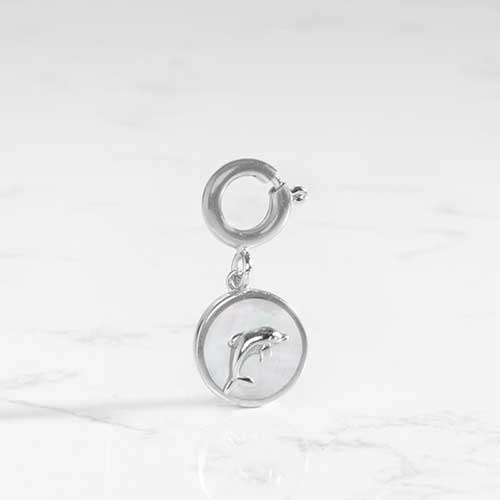 Round, silver charm with a silver dolphin inset on an inlay of mother of pearl