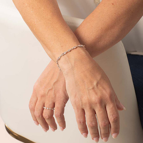 Woman wearing rose gold tone med ID bracelet with round, rectangle, and oval clear cubic zirconia crystals.