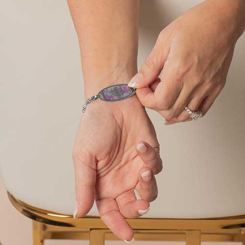 Woman showing decorative medical alert tag with lavender inlay on stainless steel