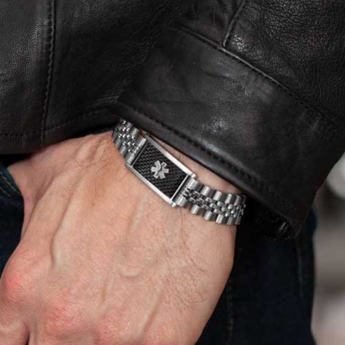 Man with thumb in pocket wearing watch style medical ID bracelet with silver links