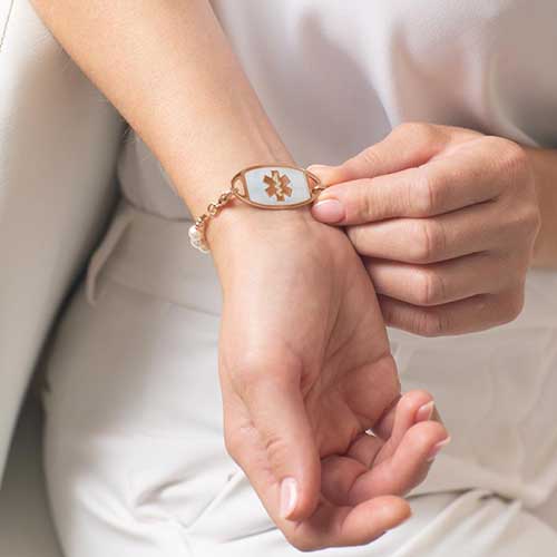 Woman showing rose gold tone stainless steel medical ID tag with rose gold tone medical caduceus.