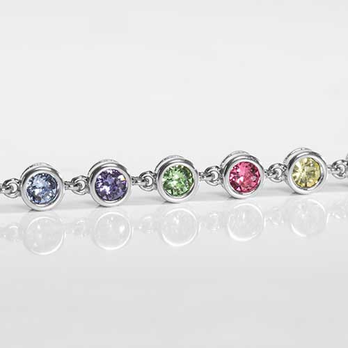 Detail of multi colored, round, bezel set crystals. Featuring crystals in blue purple, green, pink and yellow