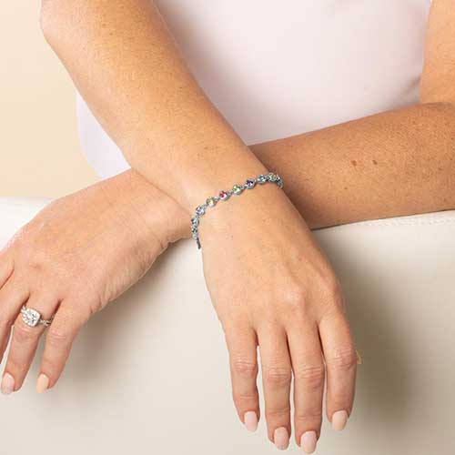 Woman wearing rhodium and palladium plated women's medical alert bracelet with multi colored, round, bezel set crystals.