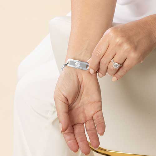 Woman wearing stainless steel medical ID tag with white medical symbol.