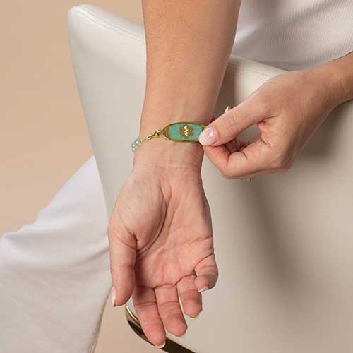 Woman showing her gold and amazonite medical ID tag