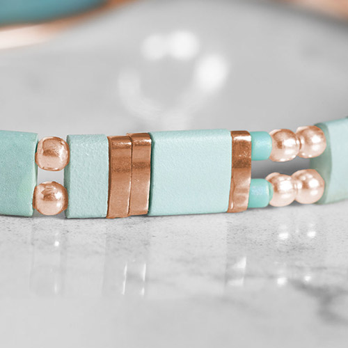 Close-up of a blue mother-of-pearl medical ID tag with a rose gold finish, showcasing an engraved medical alert symbol for safety and style.