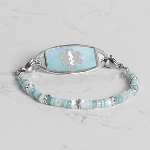 Flat lay of a silver medical ID bracelet with a mother-of-pearl inlay, highlighting its elegant design and safety features.