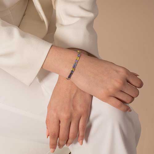 Gold medical ID tag with medical alert symbol attached to iridescent pastel beaded bracelet strand.