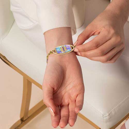 Woman wearing pastel beaded gold medical ID bracelet, displaying the engraved medical alert tag.