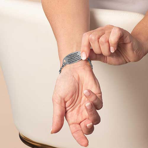 Woman displaying custom laser engraving on her stainless steel medical alert tag.