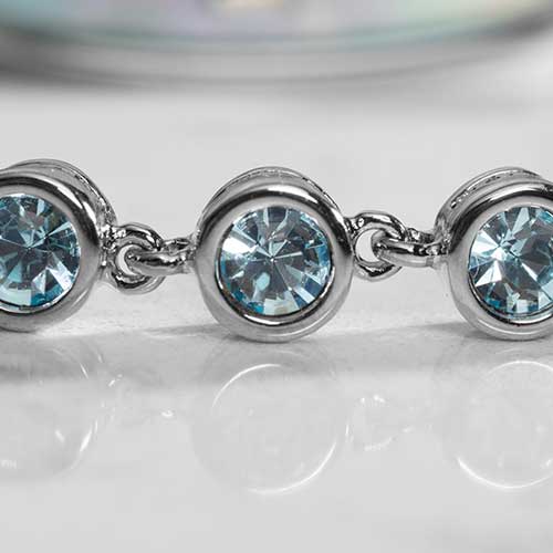 Close up of rhodium and palladium plated women's medical alert bracelet with aquamarine, round, bezel set stones.