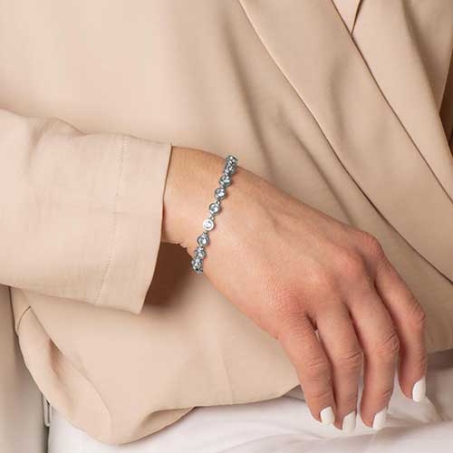 Woman wearing rhodium and palladium plated women's medical alert bracelet with aquamarine tone, round, bezel set cubic zirconia crystals.