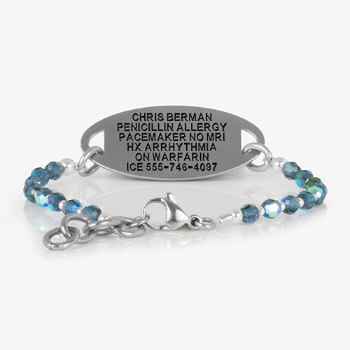 Engraved silver medical ID tag paired with abalone and blue beaded SmartStretch bracelet, showing emergency details.