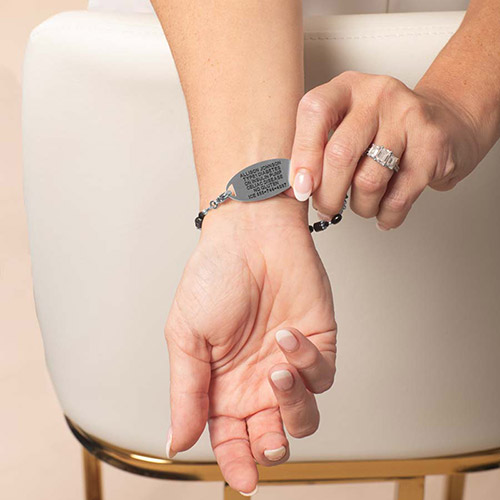 Woman wearing a Lauren’s Hope silver medical alert bracelet with black beaded strand, showing custom engraved ID tag with medical information.