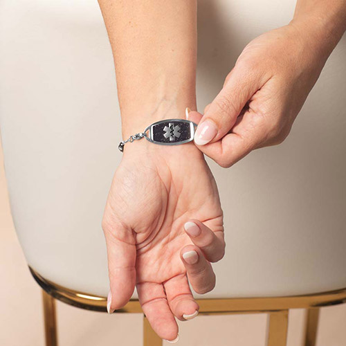 Lauren’s Hope silver medical ID tag with black enamel medical caduceus symbol on wrist, paired with Livi beaded bracelet in silver.