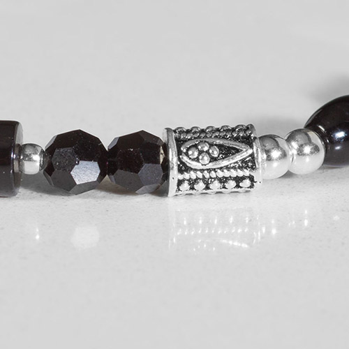 Close-up of Livi bracelet detail showing black faceted beads, ornate silver barrel bead, and smooth silver accent beads.