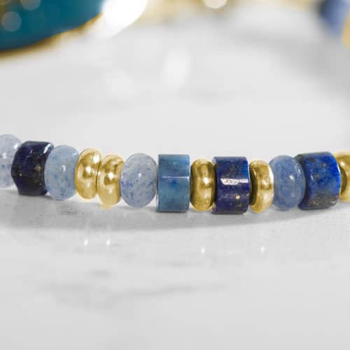 Close up of Blue and gold beaded medical ID bracelet on jewelry elastic with gold plated stainless steel lobster clasps and sapphire blue decorative med ID tag.