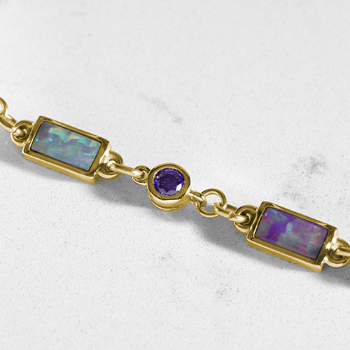 Detailed view of rectangular lilac abalone and round purple amethyst links set in gold, showcasing the vibrant color play of the stones.