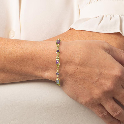 Side profile of gold bracelet on wrist, highlighting alternating lilac abalone and amethyst links in a delicate and elegant design.