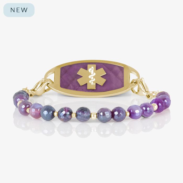 Studio image of a purple and gold medical ID bracelet featuring faceted ombré agate beads and a gold tag with purple inlay and a gold medical alert symbol.