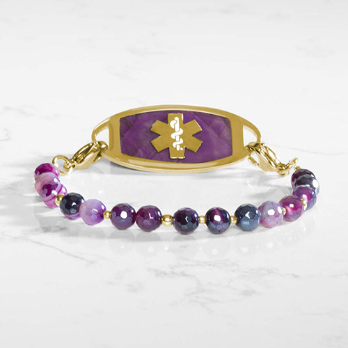 Close-up view of the faceted beaded bracelet featuring ombré purple agate beads and tiny gold spacers on a white marble surface.