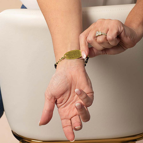 Woman wearing Lauren’s Hope gold medical alert bracelet with black and gold beads, showing custom engraved gold ID tag.