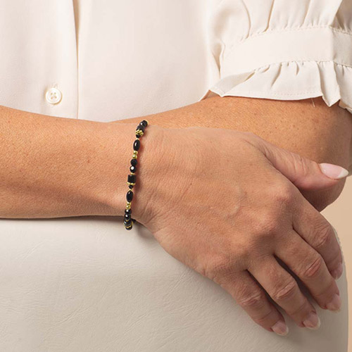 Close-up of black and gold beaded medical ID bracelet on woman’s wrist, featuring Lauren’s Hope Livi style in gold finish.