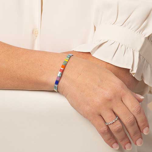 Woman wearing multicolored stretch bracelet with orange, blue, and silver accents.