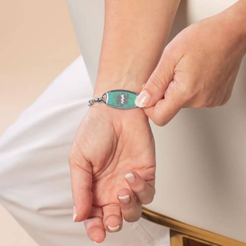 Woman showing Turquoise blue and Silver medical ID alert tag with Silver caduceus symbol
