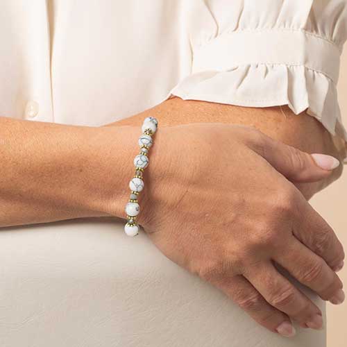 Woman wearing a howlite and gold beaded, medical ID bracelet.