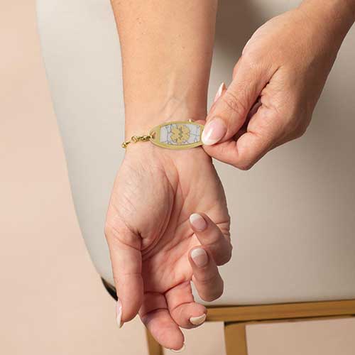 Woman displaying her gold toned, howlite inlaid medical ID tag.
