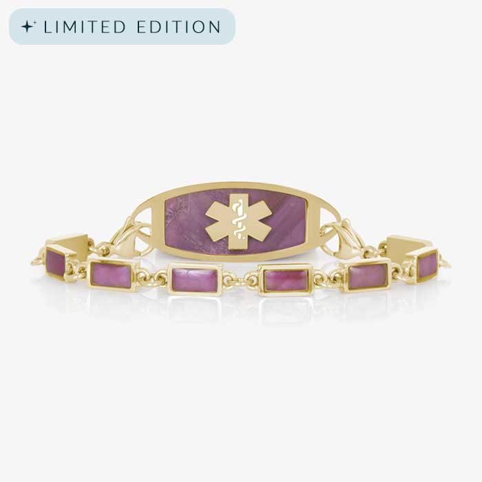 Gold medical ID bracelet featuring purple rectangular inlays and a coordinating tag with a marbled purple background engraved with a gold medical caduceus symbol.