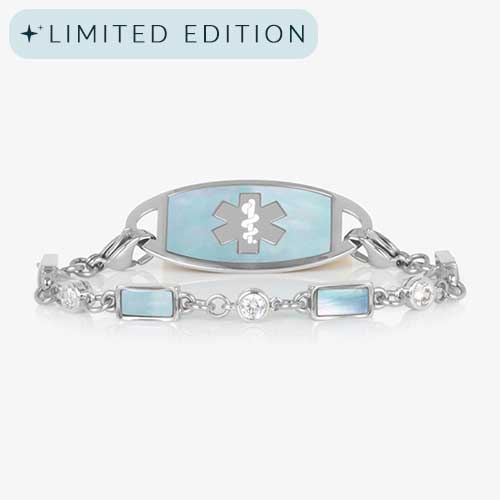 Silver medical ID bracelet with blue mother-of-pearl inlay tag and clear and iridescent rectangular gemstone accents, displayed on a white background.
