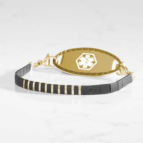 Gold medical ID bracelet featuring black and gold tila beads and a decorative, gold tone, medical ID.