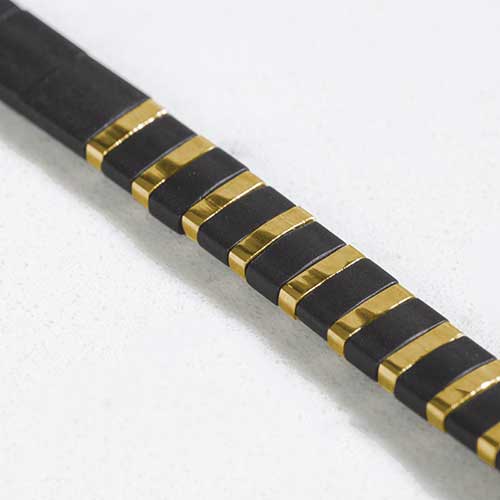 Close up of alternating black and gold tila beads.