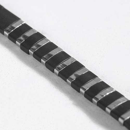 Close up of alternating black and silver tila beads.