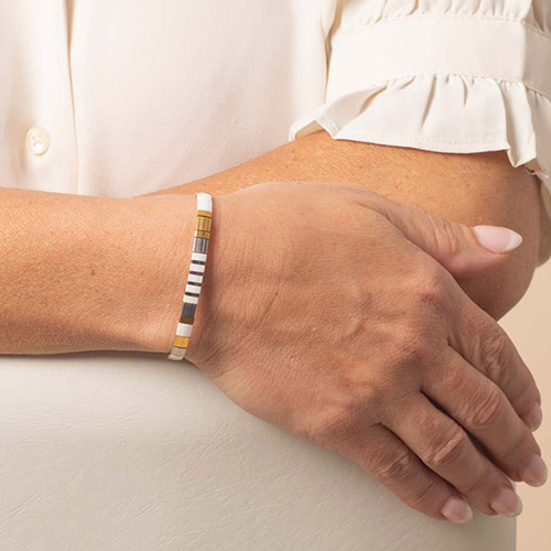 Nova Gold medical ID bracelet worn on the wrist, showcasing the minimalist striped bead strand in white, gold, and silver tones.