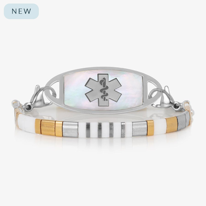 Silver medical ID bracelet with a mother-of-pearl tag and a geometric stretch strand featuring white, silver, gold, and hematite cube beads.