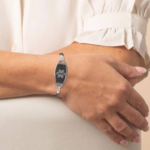 Woman wearing a silver medical ID bracelet with black beaded chain and marble inlay, combining elegant style with safety.