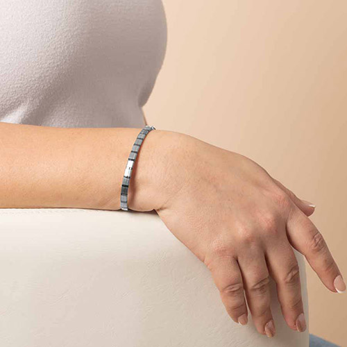 Close-up of a woman’s wrist showcasing the Vega bracelet, featuring sleek, reflective hematite cube beads in a minimalist stretch design.