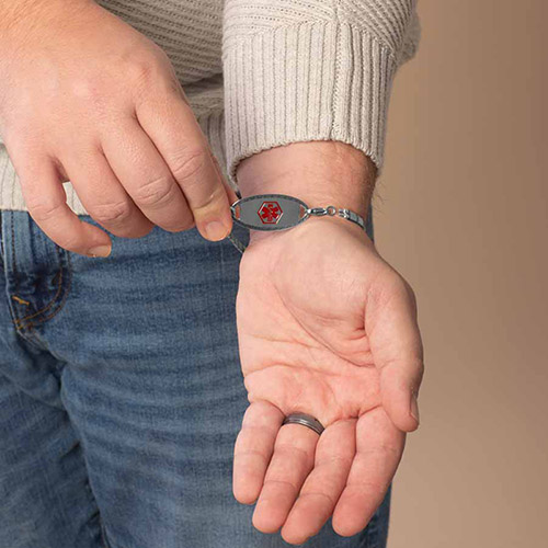 Front view of the Mercury men’s medical ID bracelet with bold red medical caduceus symbol, worn on wrist with neutral-toned sweater.