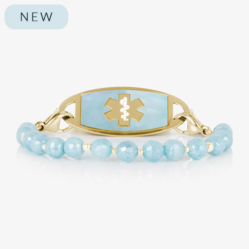 Gold medical ID bracelet with pale blue faceted gemstone beads and gold accent spacers, shown with a matching gold ID tag featuring a cloud blue inlay and cutout medical symbol.