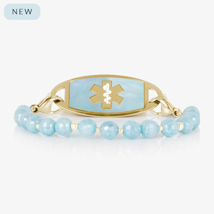 Gold medical ID bracelet with pale blue faceted gemstone beads and gold accent spacers, shown with a matching gold ID tag featuring a cloud blue inlay and cutout medical symbol.